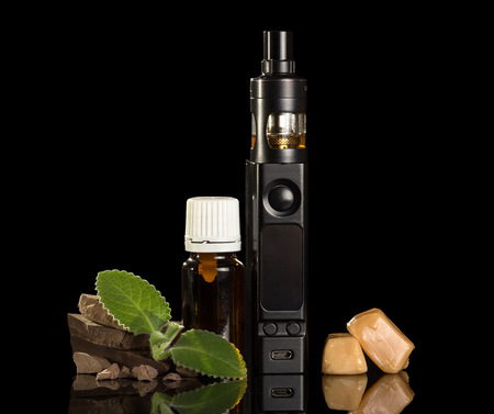 Electronic cigarette, liquid for Smoking and pieces of sweets, isolated on black backgroundの写真素材