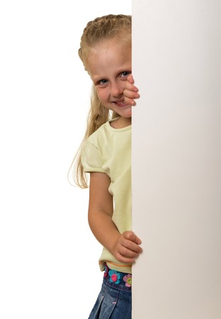 Little smiling girl peeks out from behind the banner, isolated on white backgroundの写真素材
