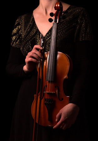Violin and bow in the hands of the musician isolated on black backgroundの写真素材