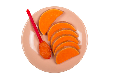 Slices of bright orange pumpkin on the plate, spoon with jam isolated on white backgroundの写真素材