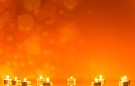 Reflection of lots of little burning candles, at the bright red shimmering backgroundの写真素材