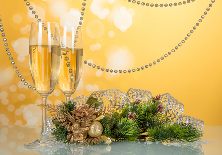 Wine glasses, pine branch, decorated with beads and ribbon, Christmas souvenir on bright yellow backgroundの写真素材