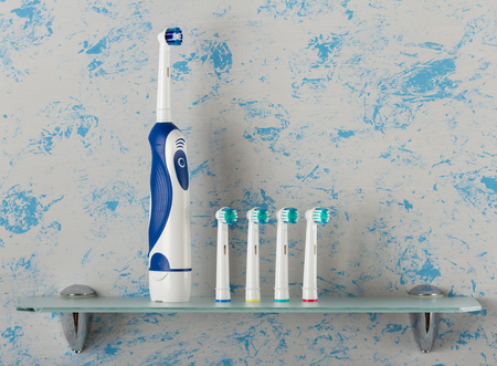 Electric toothbrush with extra nozzles of different colors on glass shelfの写真素材