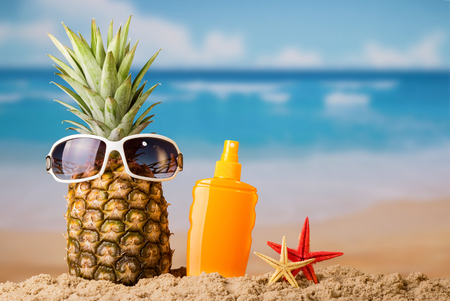 Sandy beach, tropical fruit and sunblockの写真素材