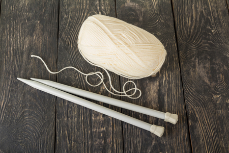 Coil of white, soft yarn and knitting needles, on wooden surfaceの写真素材