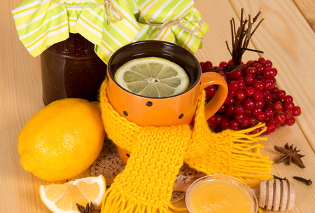 Jars of jam, viburnum berries, tea with lemon and honey, on tableの写真素材