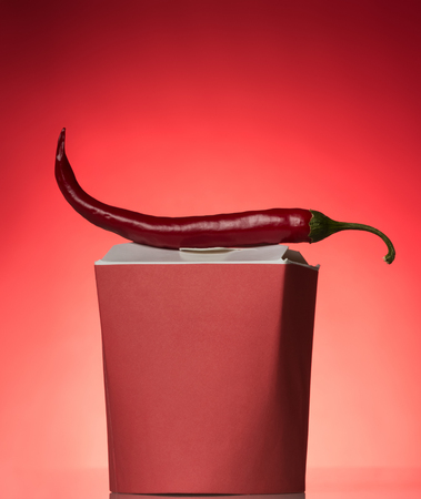 Spicy Asian food in box wok , on top of chilli, on redの写真素材
