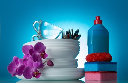 Set of clean dishes and Orchid flower, detergent, sponge, on blueの写真素材