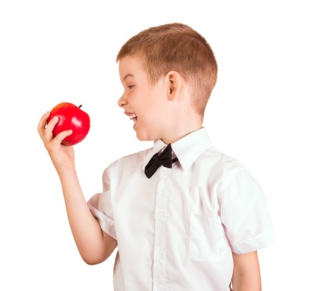 Schoolboy in shirt with butterfly wants to eat an Apple, isolated on whiteの写真素材