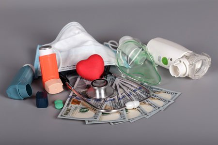 Inhalers and mask, stethoscope, money for diagnostics and treatment, on grayの写真素材