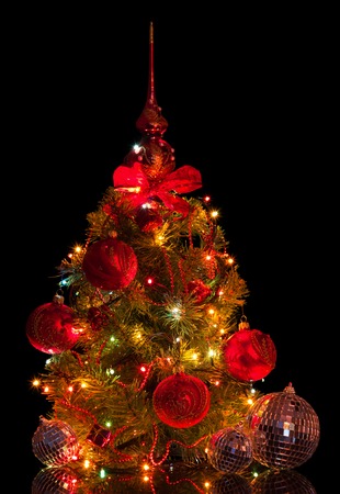 Charming small Christmas tree with mirror balls, beads and garland, isolated on blackの写真素材