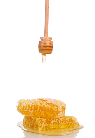 Bee honeycombs, spoon-spindle with drops of honey, isolated on whiteの写真素材