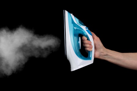 Modern electric iron with steam isolated on blackの写真素材