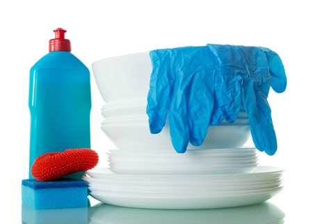 Stack of clean dishes, detergent, sponges and gloves isolated on whiteの写真素材