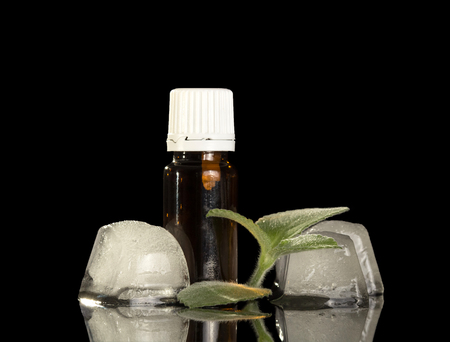 Bottle of aromatic liquid for smoking, ice cubes and mint isolated on blackの写真素材