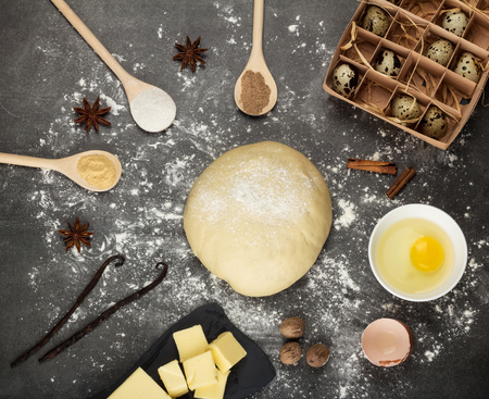 Clod finished dough, butter, eggs, spices in spoons on gray surfaceの写真素材