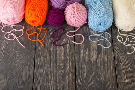 Skeins of yarn assorted colors for needlework on wooden surface