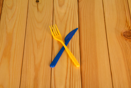 Fork and knife, plastic disposable devices, on wooden tableの写真素材