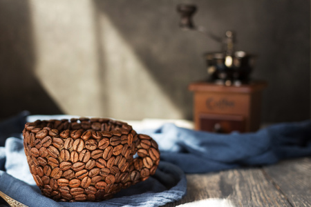 An impromptu Cup of coffee beans, manual coffee grinder on background fabricの写真素材