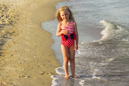 Charming little girl walking along the seashoreの写真素材