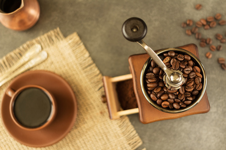 Hand coffee grinder at work, Cup of freshly brewed coffee, on grey tableの写真素材