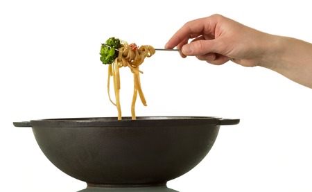 Wok pan, tasty noodles with vegetables on fork isolated on whiteの写真素材
