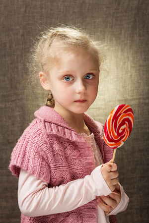 Little sad girl after illness, holds candyの写真素材