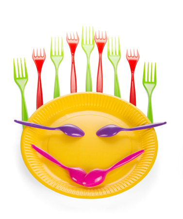 Stylized smiley face from set of disposable plastic tableware isolated on whiteの写真素材