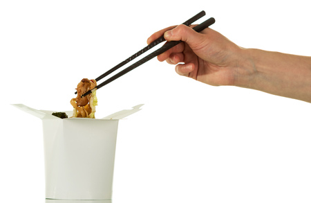 Meat with noodles and vegetables out of box-wok in woman hand isolated on whiteの写真素材