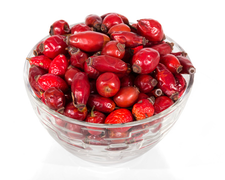 Dry rose hip fruits in glass bowl isolated on whiteの写真素材