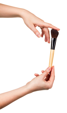Wide cosmetic brush for applying makeup Foundation in woman hands isolated on whiteの写真素材