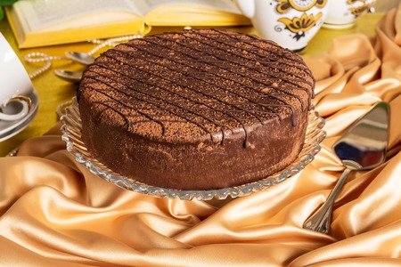 Large crystal dish with chocolate sponge cake on silk tableclothsの写真素材