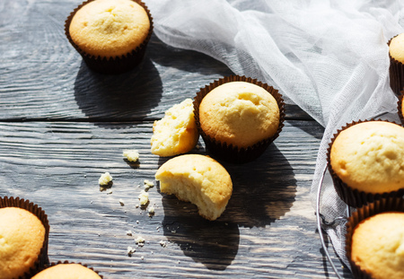Ruddy mouth-watering cupcakes in molds, beside thin white cloth, on tableの写真素材