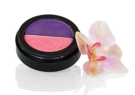 Box of two-color decorative dry cosmetics, near Orchid flower, isolated on whiteの写真素材