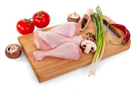 Poultry meat - chicken legs and vegetables on cutting Board isolated on whiteの写真素材
