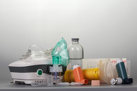 Compressor and portable inhalers, replaceable dispenser, ampoules and baby mask, on greyの写真素材