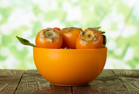 Full bowl of persimmon fruit on tableの写真素材