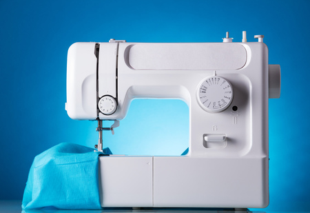 Sewing machine in work with fabric, on blueの写真素材