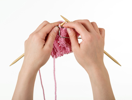Knitted fabric, knitting needles and pin in hands of woman isolated on whiteの写真素材