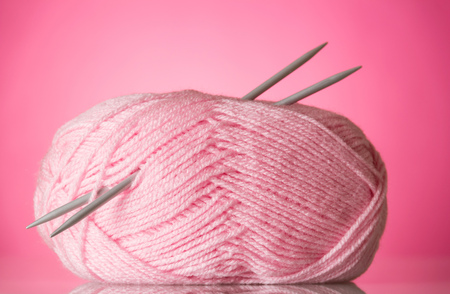 Club of soft, fluffy pink yarn and knitting needles, on pinkの写真素材