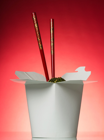 Open wok box with noodles and vegetables, chopsticks on pinkの写真素材