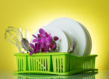 Clean plates, Cutlery and wine glasses, flowers on dryer, on yellowの写真素材