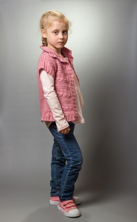 Little blonde with grey eyes shows off clothes on greyの写真素材
