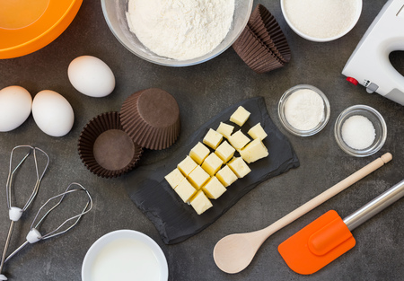 Butter, flour and eggs for biscuit, mixer and blade for preparation of dough, on work surfaceの写真素材