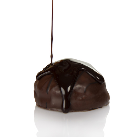 Delightful candy with praline, in streams of the melted chocolate isolated on whiteの写真素材