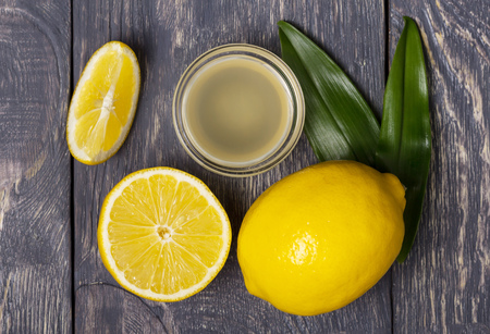 Lemon and fruit pieces, juice in bowl on wooden surfaceの写真素材