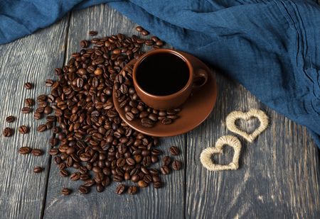 Cup of coffee and scattered grains, next to small heartsの写真素材