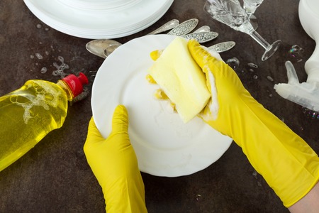 Womens hands in gloves wash dishes with detergent, on blackの写真素材