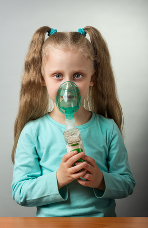 Little sick girl breathes through nebulizer, on gray backgroundの写真素材