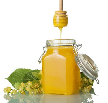 Trickle of natural honey, flowing from a spoon, Linden flowers, isolated on whiteの写真素材